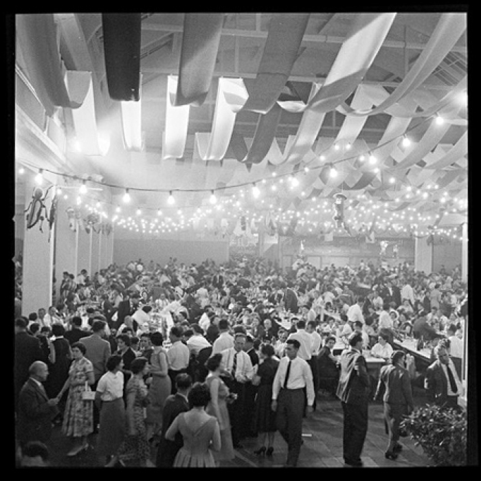 Black and white photo of people at the party in a hall.